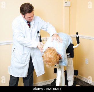 Chiropractor assists an elderly patient recovering from a back injury.  Stock Photo