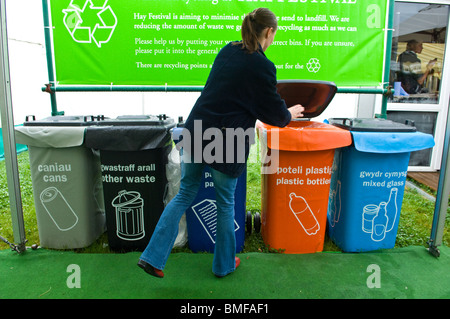 Female placing waste into coloured plastic wheelie bins used for various recyclable waste Stock Photo