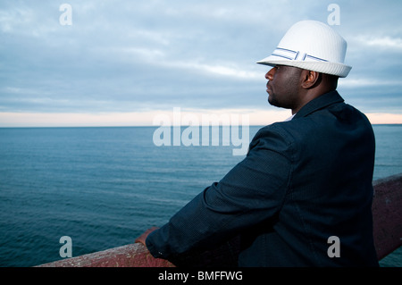 Black man wearing white hat looking over water Stock Photo