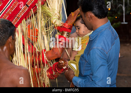 India, Kerala, Cannanore (Kannur), Theyyam, serpent deity Naga Kanni giving young child it’s first blessing Stock Photo