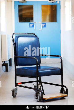 An empty wheelchair sitting in the middle of a hospital corridor Stock Photo
