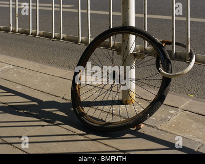 Lonely rusty bicycle wheel remains padlocked for ages to the highway fence in Beijing, China Stock Photo
