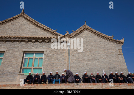 Elderly Hui people sitting beside Mageda Mosque, Mageda Village, Tongxin, Wuzhong, Ningxia Province, China Stock Photo