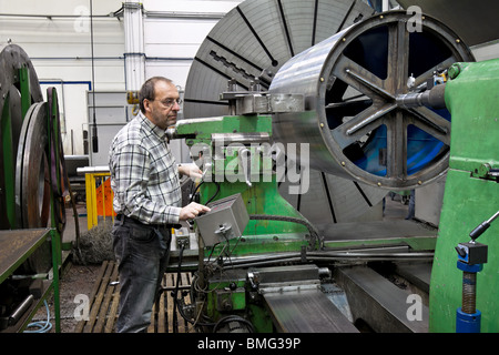 An older worker in the metal industry with CNC milling machine. Stock Photo