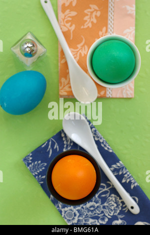 Orange and Green Easter Egg in an Eggholder, Blue Egg lying at the Side Stock Photo