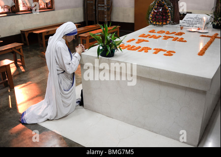 India Kolkata Calcutta, nun praying at grave of Mother Teresa at Mother ´s Teresa house, written with flowers Love until it hurts Stock Photo