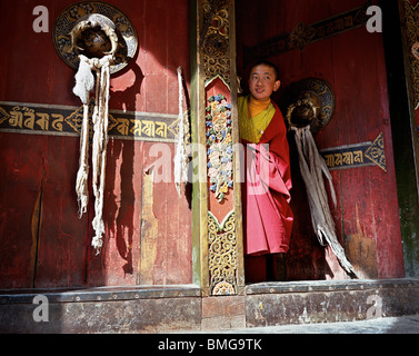 Tibetan boy lama peaking out of the gate of Dege Sutra Printing House, Garze Tibetan Autonomous Prefecture, Sichuan, China Stock Photo