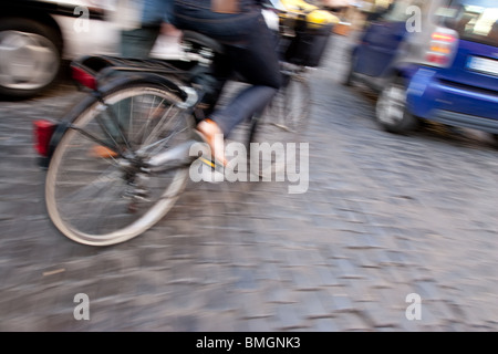 woman pedaling a bicycle in the town street of Rome Italy
