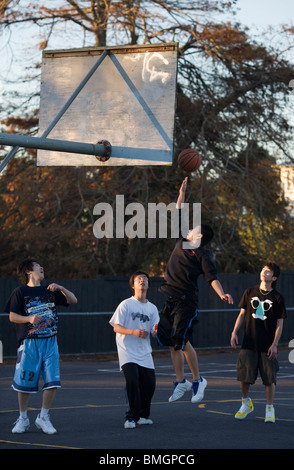 Oriental young teenagers playing basketball in the afternoon, Auckland, New Zealand Stock Photo