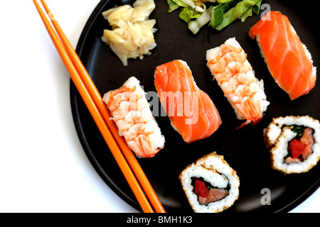 Selection Of Japanese Style Raw Fish And Rice Sushi Served On A Black Plate With Chopsticks Isolated Against A White Background With A Clipping Path Stock Photo