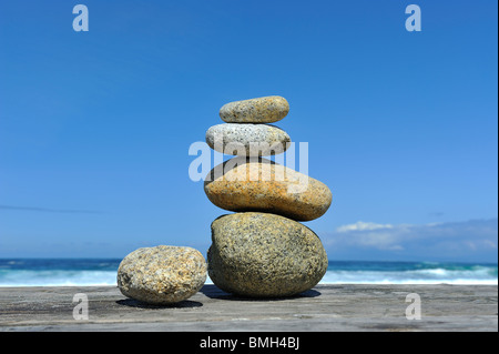 Peaceful symbol Zen stones rocks stacked at beach cairn against a blue sky and ocean 17 Mile Drive Pebble Beach California USA Stock Photo