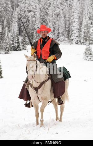 cowboy hunter riding white horse in snow hunting with rifle Stock Photo ...