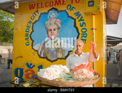 A man selling garlands of jasmine flowers at the bus station In Mysore India Stock Photo