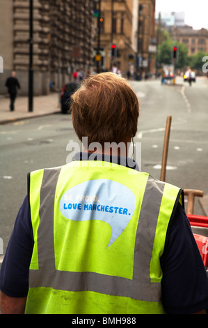 Street cleaner with slogan 'Be proud love Manchester' printed on the back of his vest Stock Photo