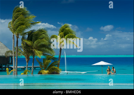 A couple is sitting by the pool, in a hotel resort and chatting Stock Photo