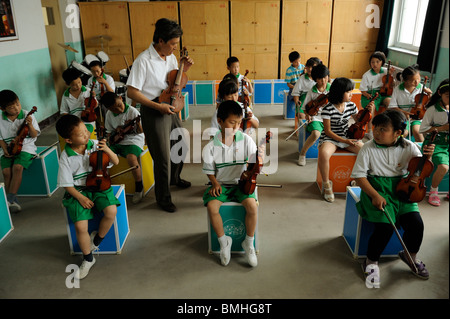 Mr. Gao Defa teaching students to play violins during a music lesson at Dawangwu primary school in Pinggu, Beijing, China. 2010 Stock Photo
