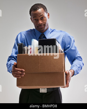 Businessman holding a box of office supplies Stock Photo