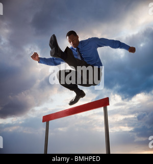 Businessman jumping over a hurdle Stock Photo