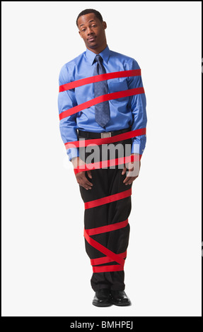 Businessman wrapped in red tape Stock Photo