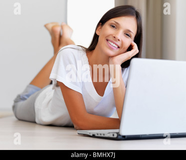 Smiling attractive woman lying on bed using laptop Stock Photo - Alamy