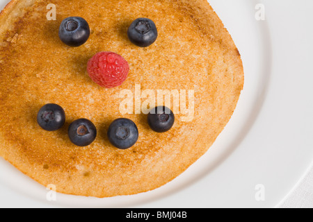 Pancake with smiley face made from blueberries and raspberry Stock Photo
