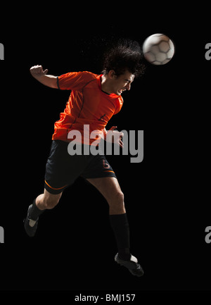 Professional football or soccer player in action on stadium with  flashlights, kicking ball for winning goal, wide angle. Concept of sport,  competition, motion, overcoming. Field presence effect. Stock Photo