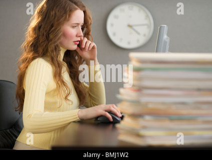 Overworked woman in cubicle Stock Photo