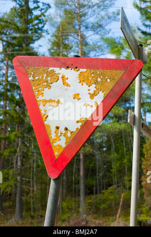 Priority road sign overgrown with moss and lichen Stock Photo