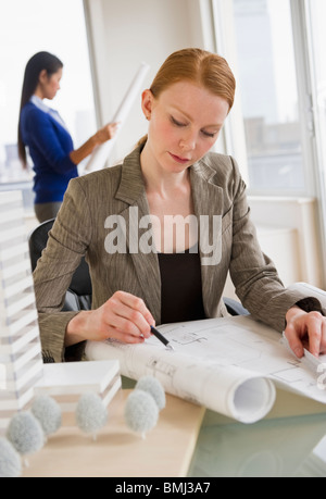 Female architect looking at blueprints Stock Photo