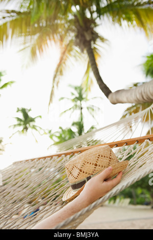 Hand holding straw hat in hammock Stock Photo