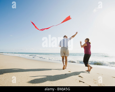 Couple flying kite on beach Stock Photo