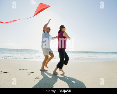 Couple flying kite on beach Stock Photo
