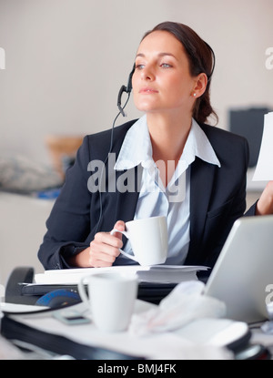 Businesswoman drinking coffee at desk Stock Photo