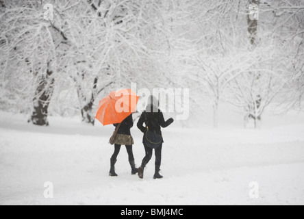 Two girls walking through snowy park Stock Photo