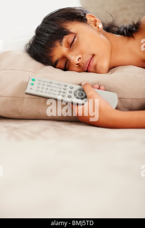 Young woman holding remote control while sleeping Stock Photo