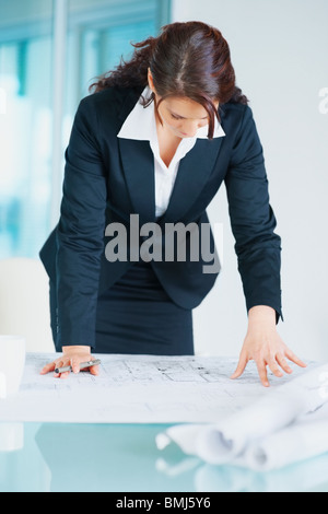 Businesswoman looking at blueprints Stock Photo