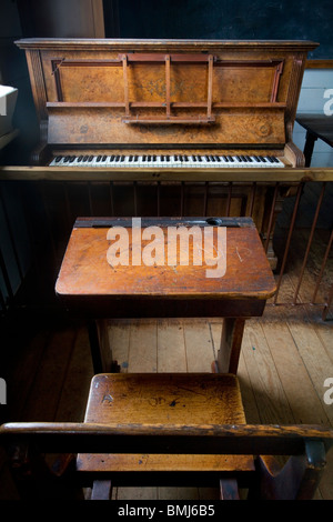 A nineteenth (XIX) century (1800s) classroom with wooden benches, a piano and a blackboard, Auckland, New Zealand Stock Photo