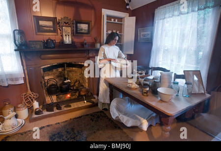 A woman batting a mix in a nineteenth (XIX) century (1800s) kitchen, Auckland, New Zealand Stock Photo