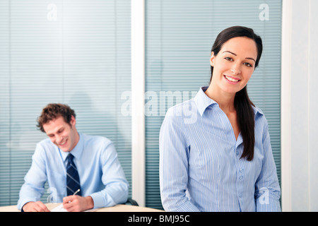 Male and female office workers, she is smiling to the camera. Stock Photo