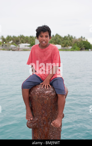 A Marshallese boy sits on a pylon on the jetty at Jabor, Jaluit Atoll, Marshall Islands Stock Photo