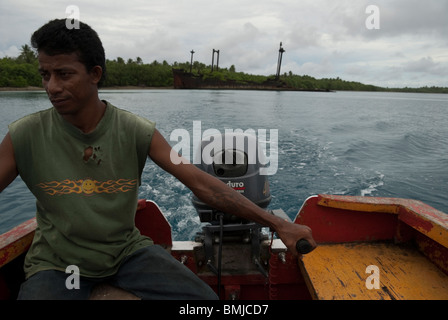 A Marshallese man steers his outboard away from a WWII wreck near Imej on Jaluit Atoll, Marshall Islands Stock Photo