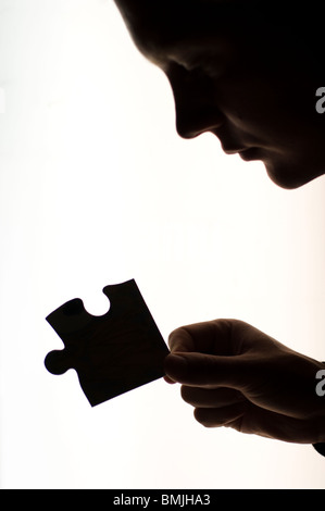 Silhouette of woman holding jigsaw piece, side view Stock Photo