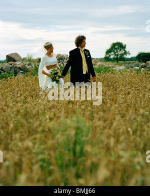 Scandinavia, Sweden, Oland, Bride and groom walking in field Stock Photo