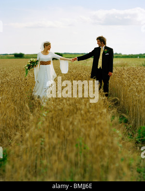 Scandinavia, Sweden, Oland, Bride and groom walking in field Stock Photo