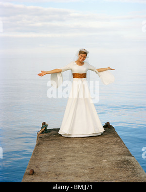 Scandinavia, Sweden, Oland, Bride standing on jetty arms outstretched, smiling, portrait Stock Photo