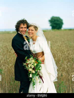 Scandinavia, Sweden, Oland, Bride and groom standing in field, smiling, portrait Stock Photo