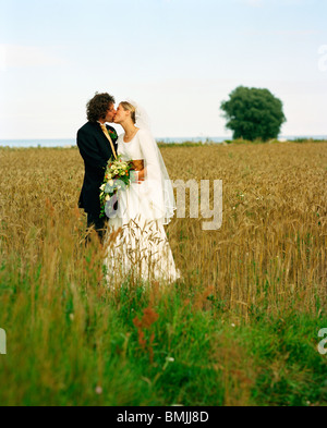 Scandinavia, Sweden, Oland, Bride and groom kissing in field Stock Photo