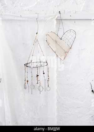Scandinavia, Sweden, Stockholm, Heart shape and wind chime hanging against white wall Stock Photo