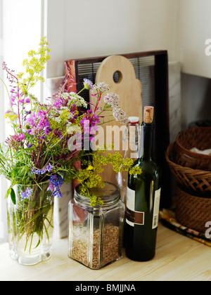 Scandinavia, Sweden, Flowers in vase and wine bottles, close-up Stock Photo