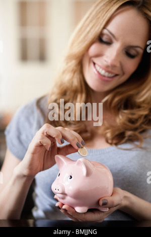 Woman saving money in piggy bank Stock Photo